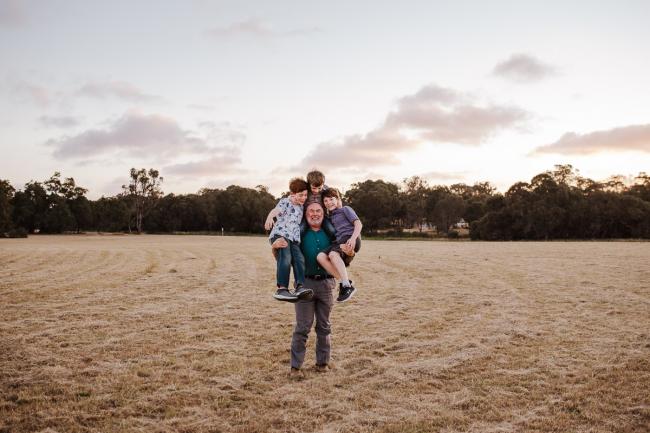 Grandfather carrying his 3 grandsons during golden hour family photography session at Perry's Paddock Perth