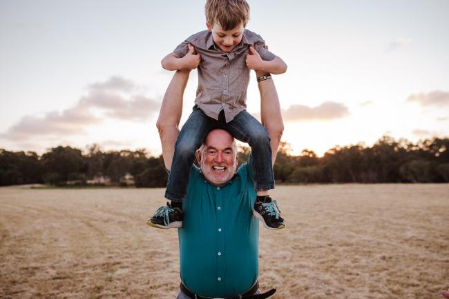 Grandfather lifting his grandson in the air during golden hour family photography session at Perry's Paddock Perth