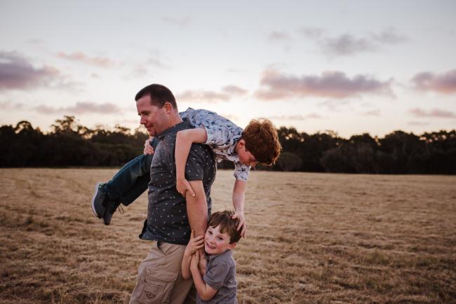 Father carrying his son over his shoulder during golden hour family photography session at Perry's Paddock Perth