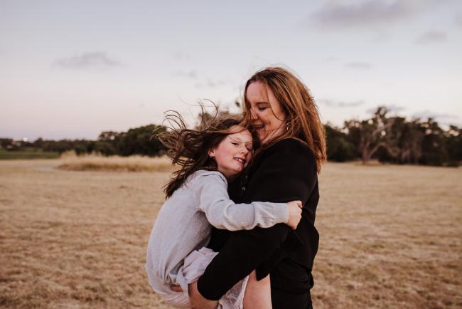 Mother carrying her daughter during golden hour family photography session at Perry's Paddock Perth