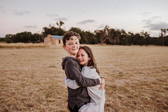 Siblings cuddling during golden hour family photography session at Perry's Paddock Perth