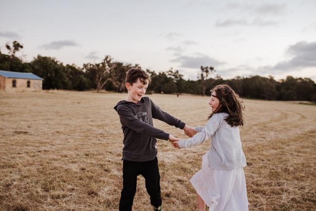Siblings spinning during golden hour family photography session at Perry's Paddock Perth