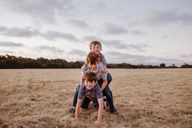 Brothers piled on top of each other during golden hour family photography session at Perry's Paddock Perth