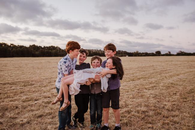 Cousins carrying their female cousin during golden hour family photography session at Perry's Paddock Perth
