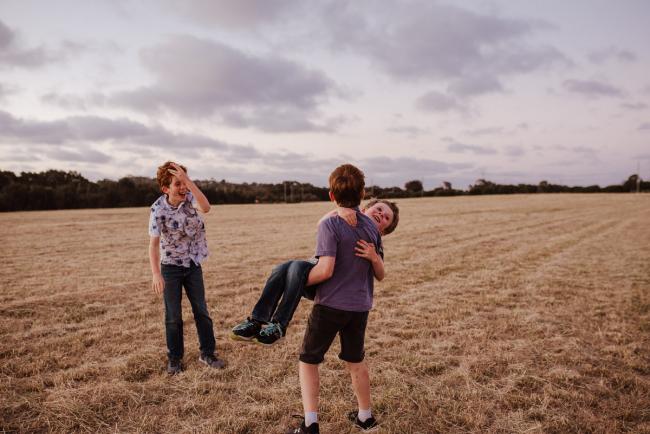 Brother spinning his younger brother around during golden hour family photography session at Perry's Paddock Perth