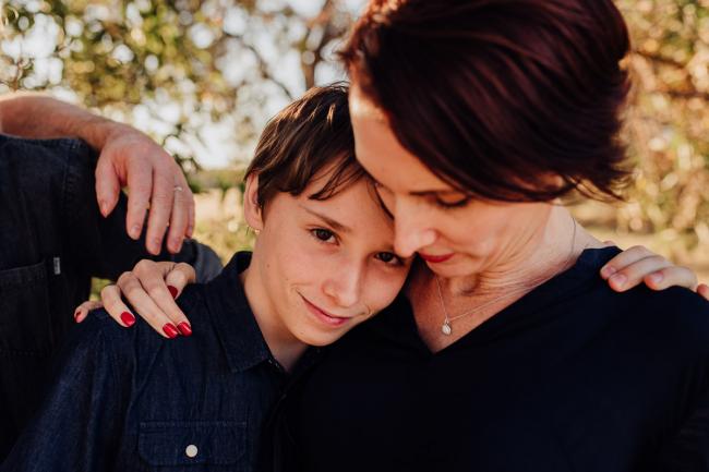 Boy resting his head on his mothers shoulder during an extended family photography session at Perry's Paddock in Perth