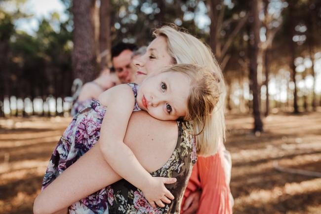 Little girl draped over her mothers shoulder during an extended family photography session at The Pines Wanneroo in Perth