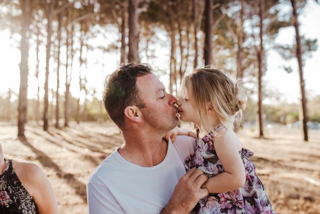 Father and daughter kissing during an extended family photography session at The Pines Wanneroo in Perth