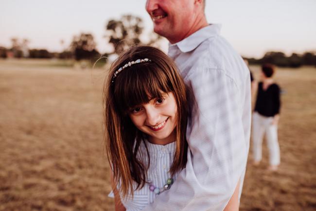 Little girl in her fathers arms during an extended family photography session at Perry's Paddock in Perth