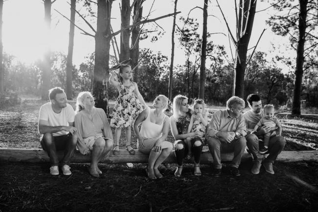 Black and white group shot sitting on a log during an extended family photography session at The Pines Wanneroo in Perth