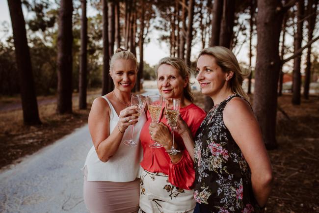 Three women standing with champagne glasses during an extended family photography session at The Pines Wanneroo in Perth