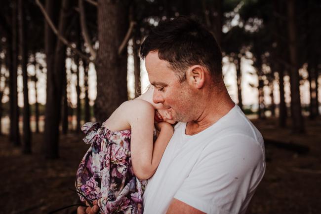 Daughter hugging into her father's chest during an extended family photography session at The Pines Wanneroo in Perth