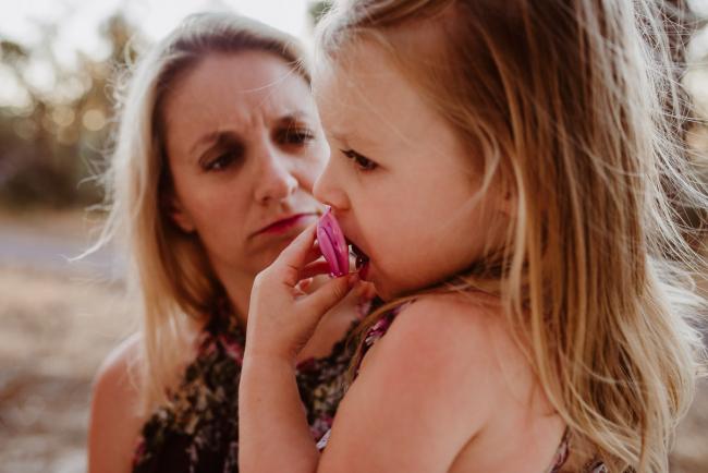 Daughter crying with a dummy as her mother frowns during an extended family photography session at The Pines Wanneroo in Perth