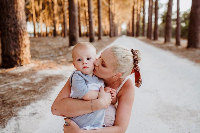 Mother kissing her son during an extended family photography session at The Pines Wanneroo in Perth