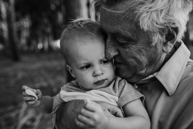 Black and white image of grandfather pressing his face against his grandson during an extended family photography session at The Pines Wanneroo in Perth