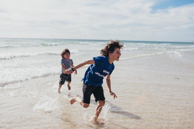 Two little boys running out of the beach with Perth family photographer