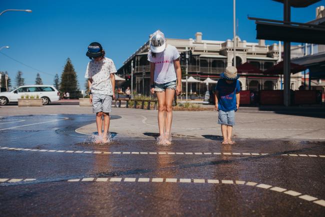 Three children standing in a water play area with Perth family photographer