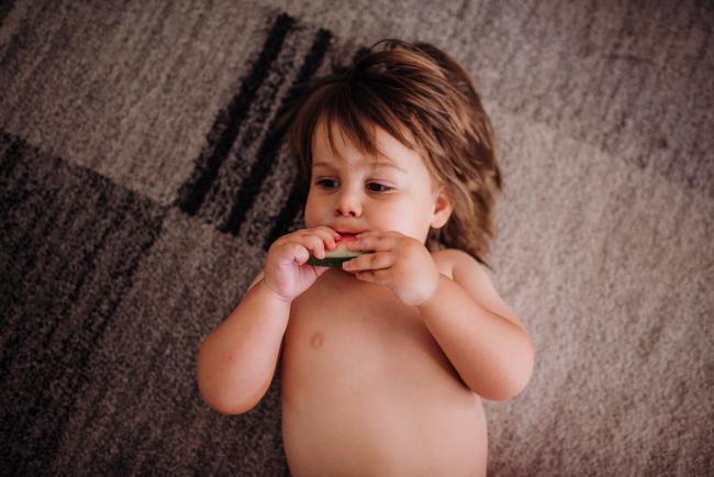 Little boy laying on the ground eating watermelon with Perth family photographer