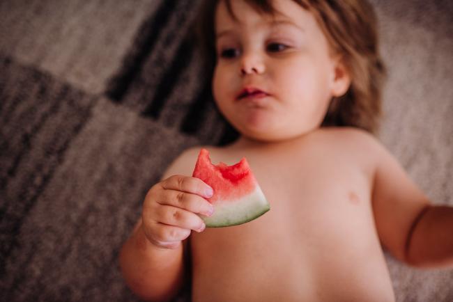 Little boy laying on the ground eating watermelon with Perth family photographer