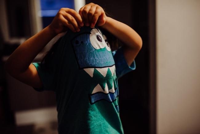 Little boy pulling pyjama top over his head with Perth family photographer