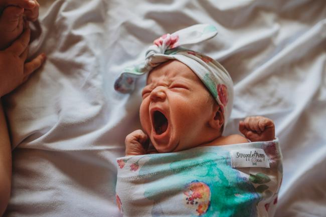 New baby in a wrap and headband yawns during a Perth Fresh 48 photography session