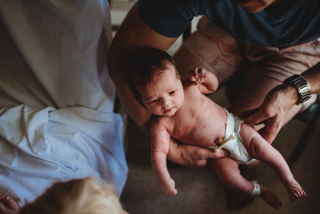 New baby in a nappy held by her dad during a Perth Fresh 48 photography session