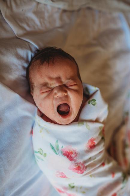 New baby in a floral wrap and yawning during a Perth Fresh 48 photography session