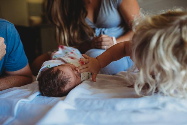 Big sister touches the nose of her new baby sister during a Perth Fresh 48 photography session