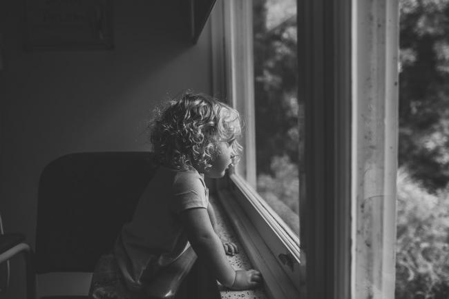 Black and white image of little girl looking out the window during a Perth Fresh 48 photography session