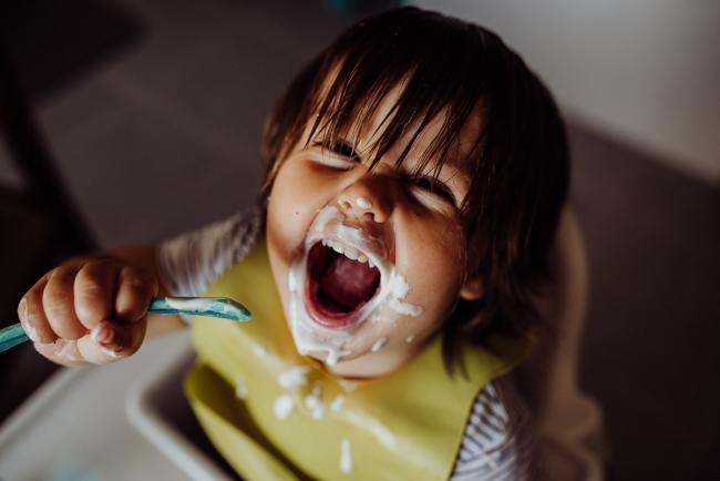 Little boy smiling up at the camera with yoghurt around his mouth with Perth family photographer