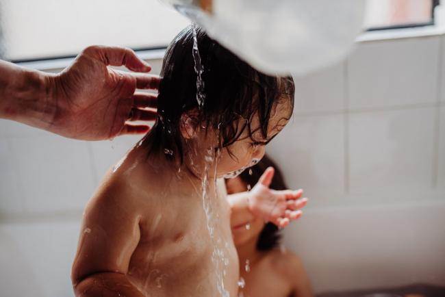 Little boy having water poured over his head during his bath with Perth family photographer
