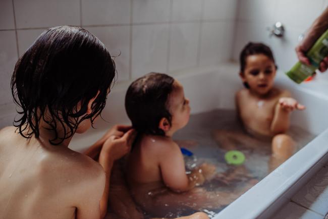 Three little boys in the bath, with one boy playing with the hair of another little boy with Perth family photographer