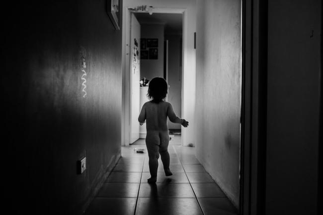 Black and white image of toddler running down the hallway towards the bath with Perth family photographer