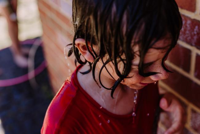 Close up of boy with soaking wet hair during a water fight with Perth family photographer