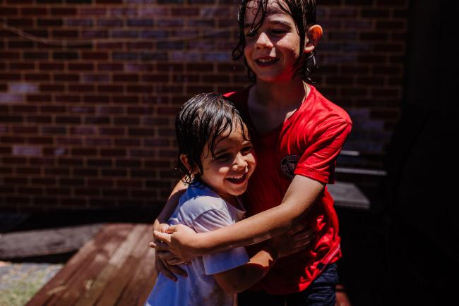 Two soaking boys hugging after a water fight with Perth family photographer