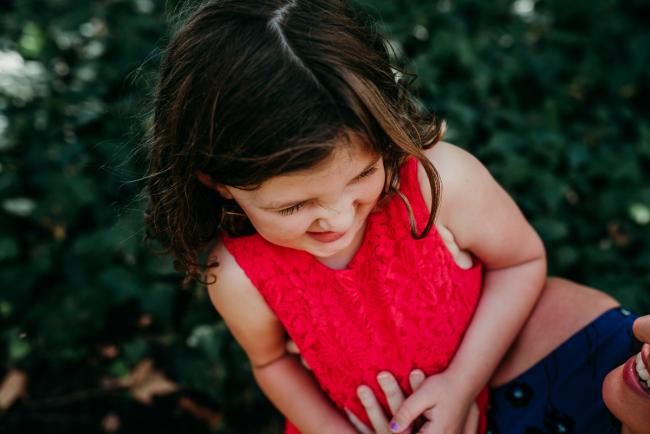 Family-Photographer-Perth-Hyde-Park-18-of-34 Close up of little girl in a red dress laughing during a Perth family photography session at Hyde Park