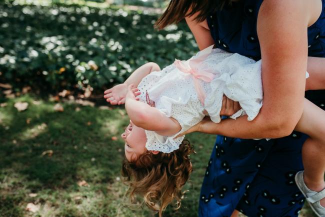 Family-Photographer-Perth-Hyde-Park-22-of-34 Little girl bending backwards in the arms of her mother during a Perth family photography session at Hyde Park