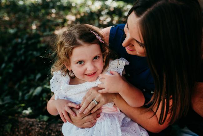 Family-Photographer-Perth-Hyde-Park-4-of-34 Little girl on her mother's lap and smiling as she looks up at the camera during a Perth family photography session at Hyde Park