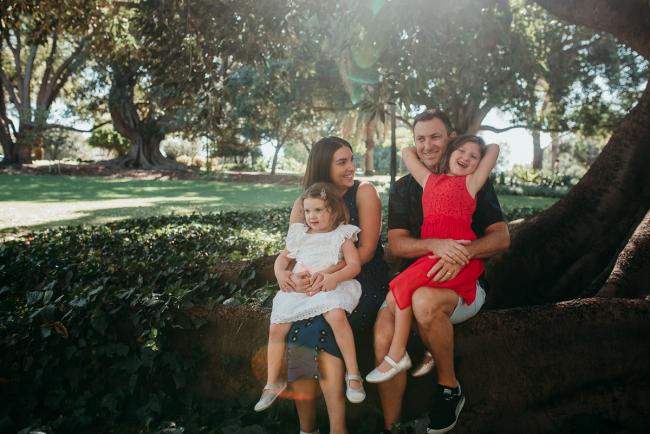 Family of four sitting on a tree during a Perth family photography session at Hyde Park