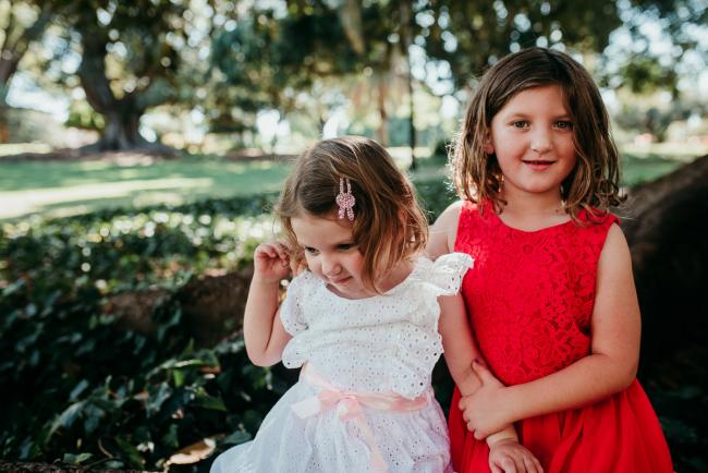 Family-Photographer-Perth-Hyde-Park-6-of-34 Two young sisters sitting on a tree during a Perth family photography session at Hyde Park