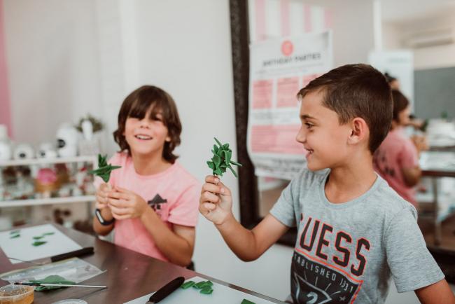 Family-Photography-Perth-14-of-25 Two boys holding up fondant creations during a Birthday party at Cakes Tinz 'n' Thingz with Perth family photographer