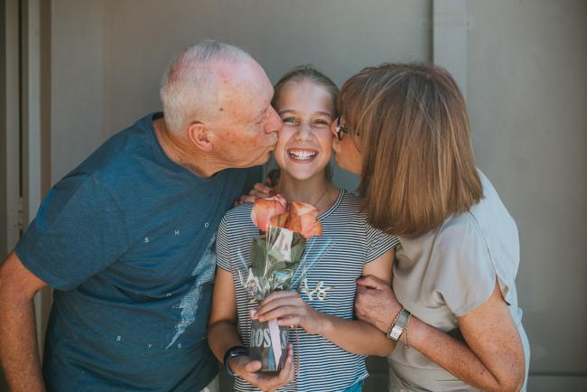 Family-Photography-Perth-2-of-25 Nanna and Grandad kissing their granddaughter as she holds roses with Perth family photographer
