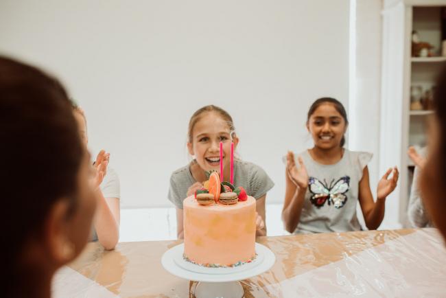 Family-Photography-Perth-23-of-25 Girl watching the candles blow out on her cake during a Birthday party at Cakes Tinz 'n' Thingz with Perth family photographer