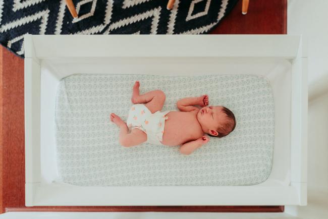 top down image of a new baby wearing a nappy in their bassinet during a Perth newborn lifestyle photography session