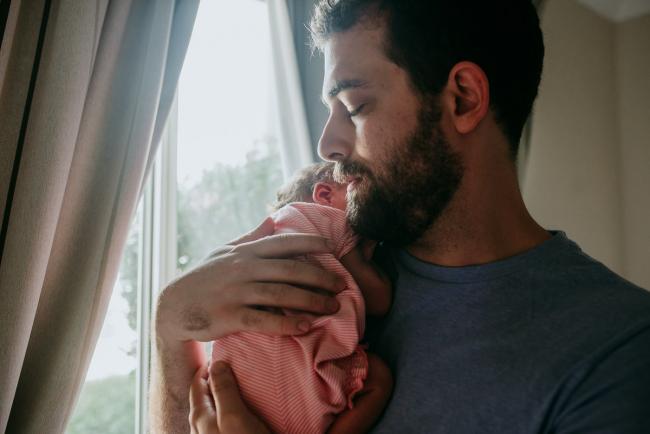 Father holding new baby up on his chest during a Perth newborn lifestyle photography session