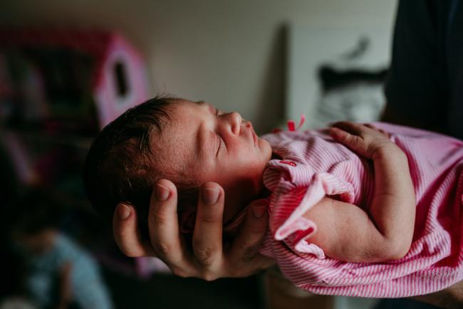 New baby being held out by her father during a Perth newborn lifestyle photography session