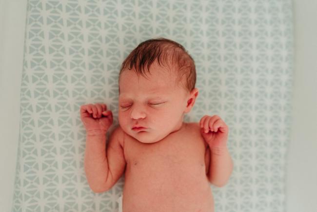 Top down image of a topless baby sleeping in her bassinet during a Perth newborn lifestyle photography session