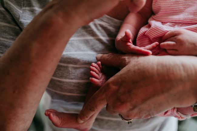 Close up of new baby's hands and feet as grandmother holds her during a Perth newborn lifestyle photography session