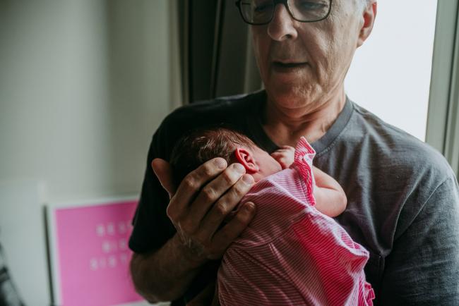 Grandfather holding his new granddaughter to his chest during a Perth newborn lifestyle photography session