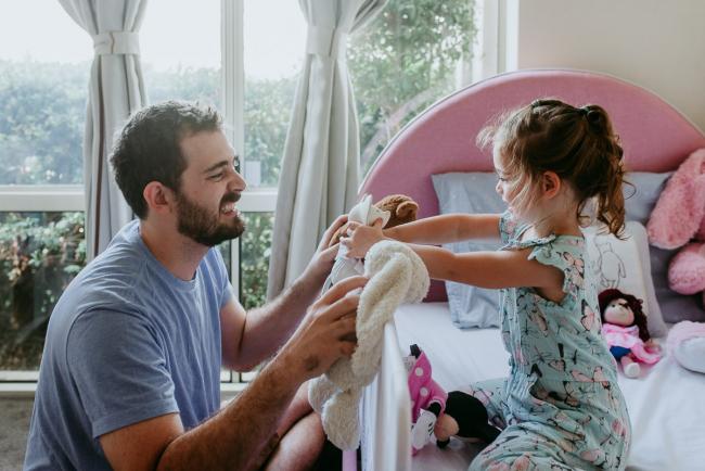 Little girl and dad playing with her toys on her bed during a Perth newborn lifestyle photography session